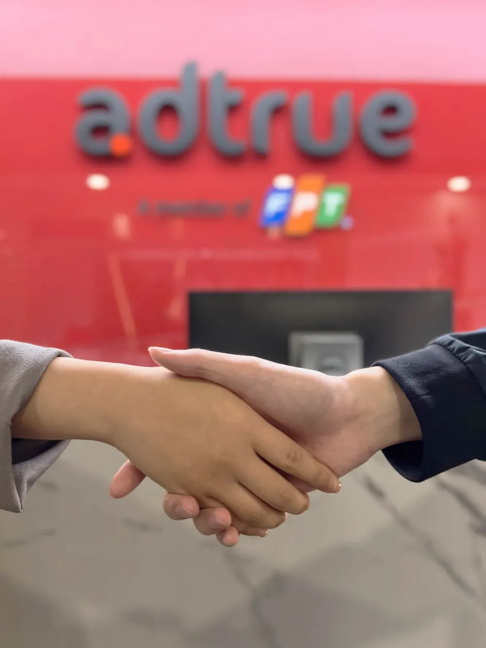 A handshake in front of the AdTrue logo